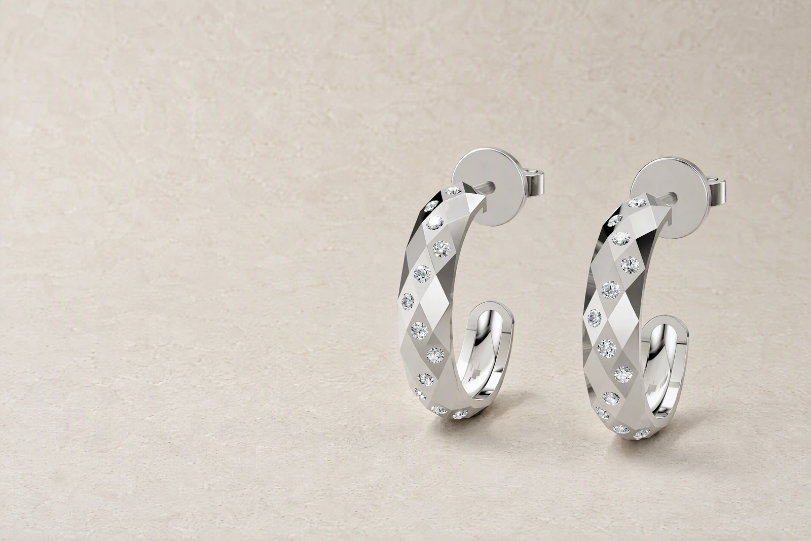 The Facetta Multi Stone Hoops standing side by side on pale limestone, their faceted bands set with rows of small clear stones