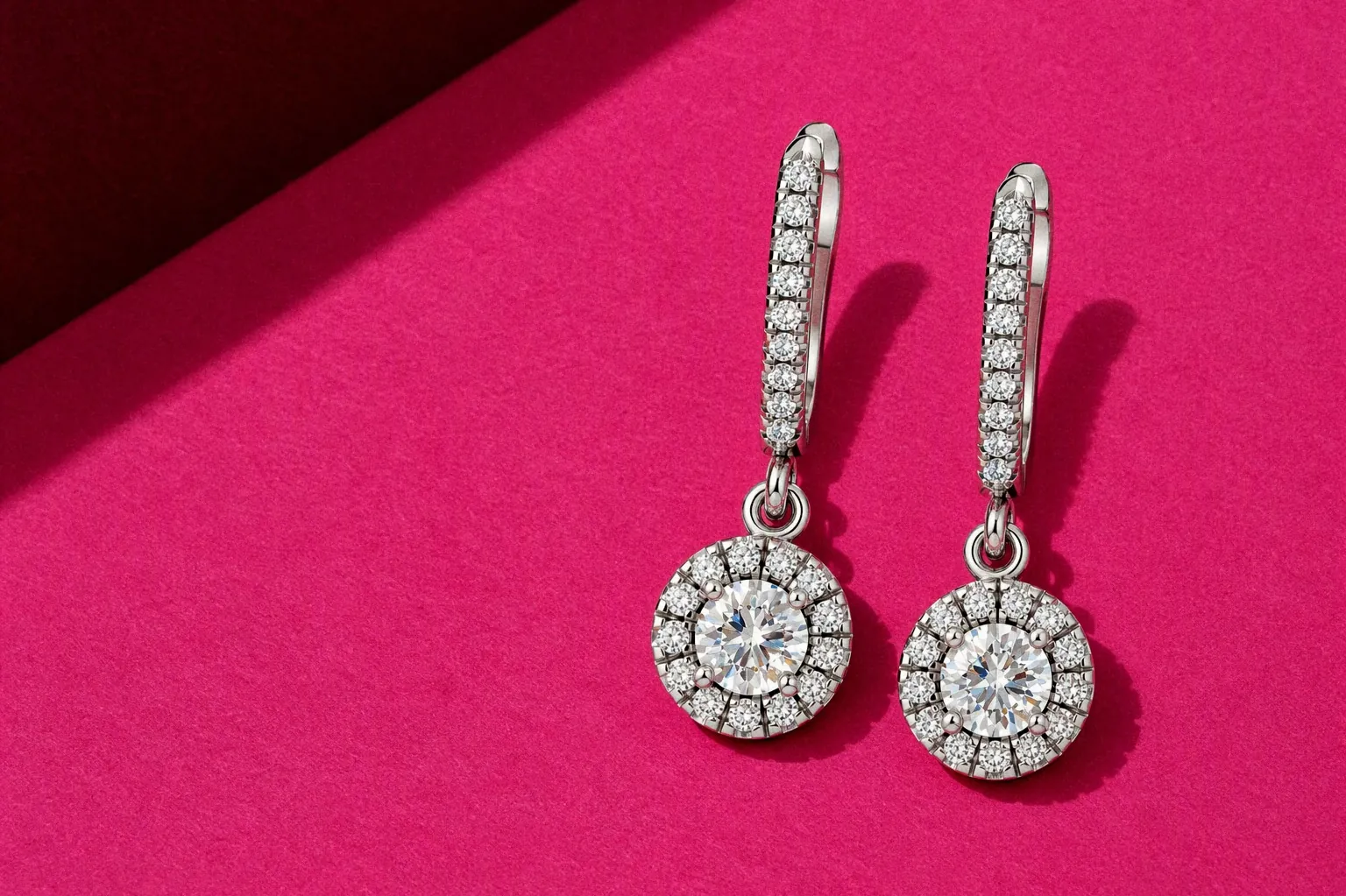 The Celeste Drop Earrings laid on pink paper
