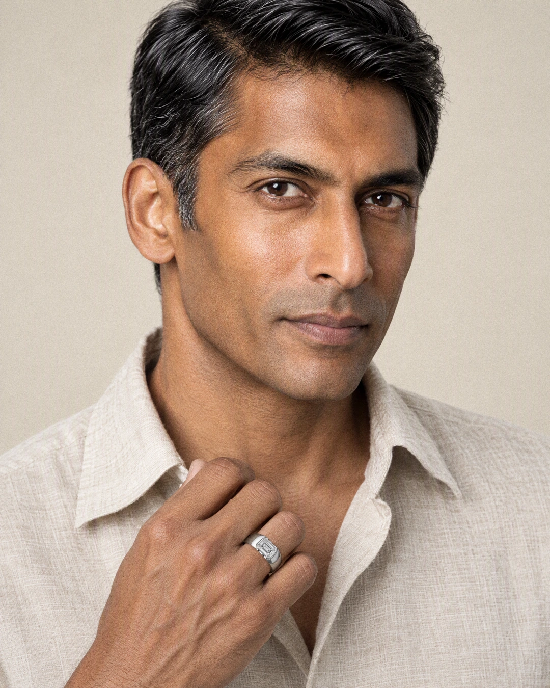 A man wearing the Frame Solitaire Ring, its emerald-cut stone set in a raised frame