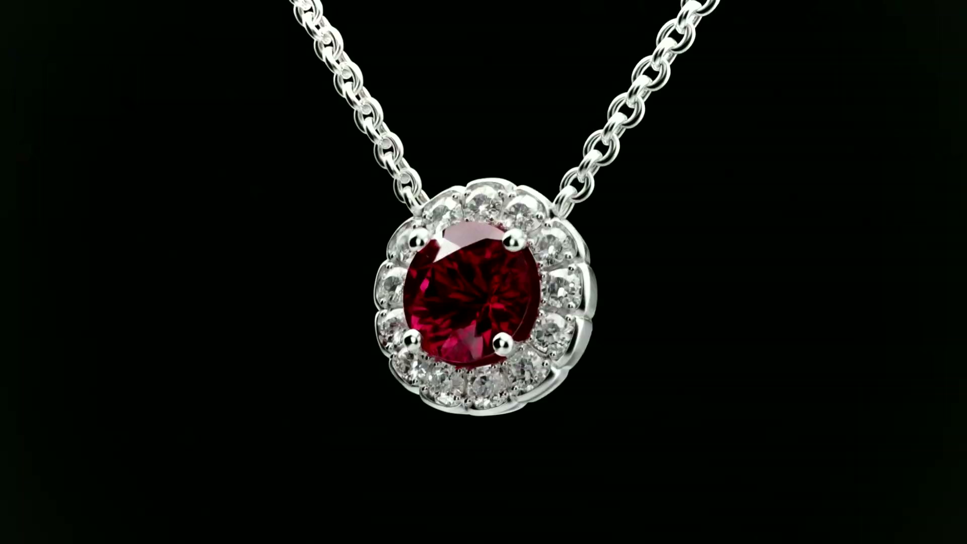 The Celeste Halo Pendant with a red stone, hanging on its chain against black