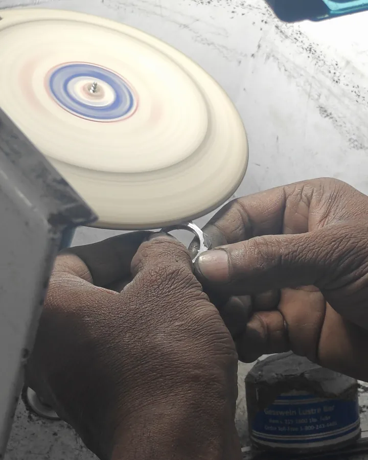 Hands holding a ring to a spinning polishing wheel